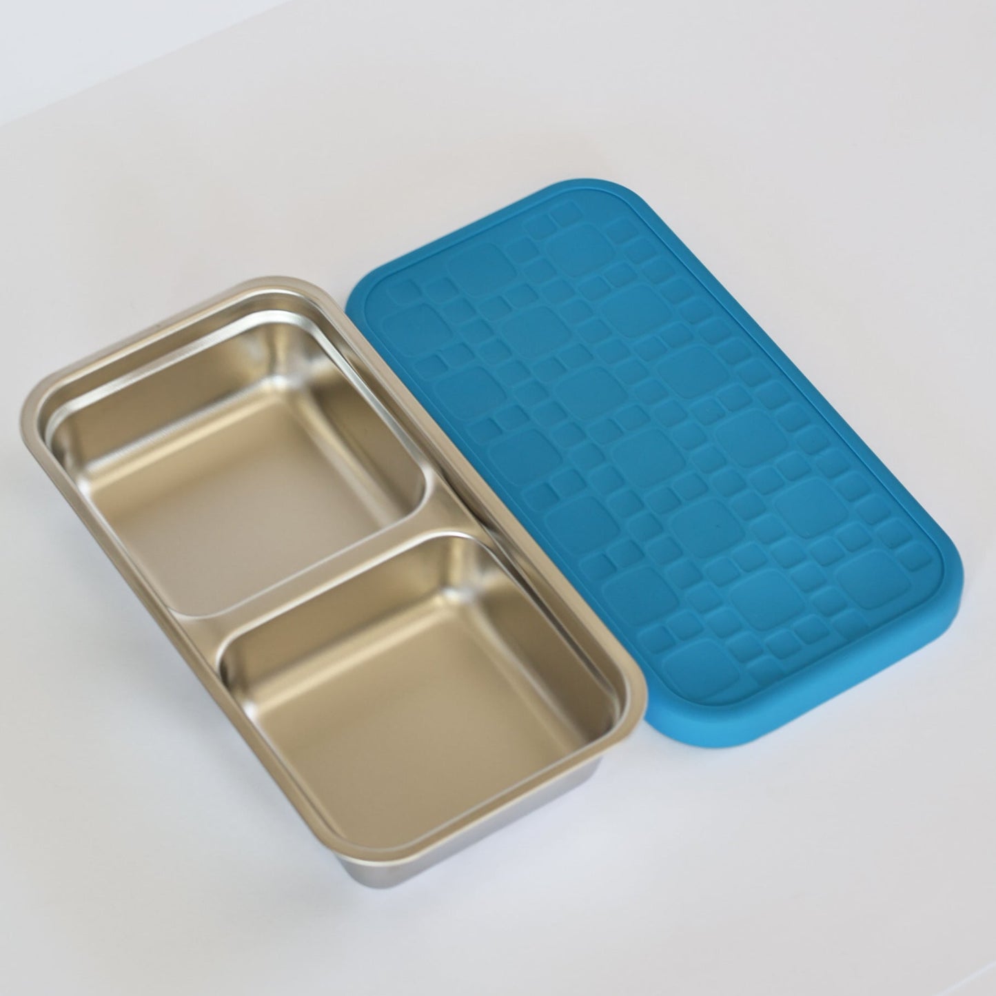 Stainless steel compartmentalized tray with a blue lid on a white background